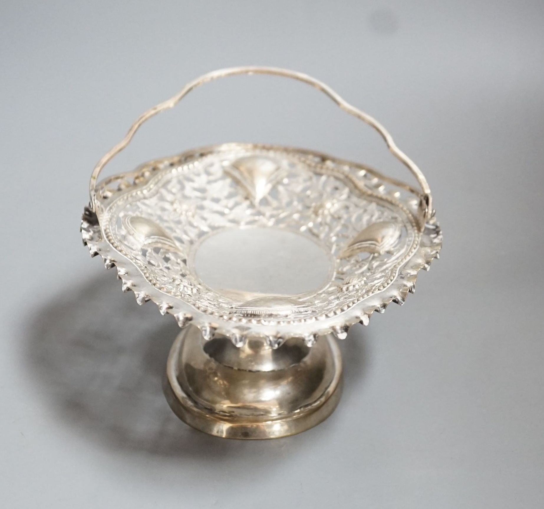 A Chinese pierced and embossed white metal shaped oval pedestal basket, length 21.6cm, 9oz, signed on base.